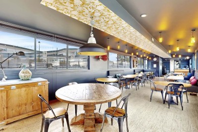 Miniature Location salle Tain-l'Hermitage (Drôme) - La Péniche #2 Terrasse en bois avec tables et chaises pliantes roses sous de grands parasols, entourée de plantes vertes.