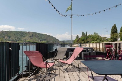 Miniature Location salle Tain-l'Hermitage (Drôme) - La Péniche #23 Terrasse en bois avec tables et chaises pliantes roses sous de grands parasols, entourée de plantes vertes.
