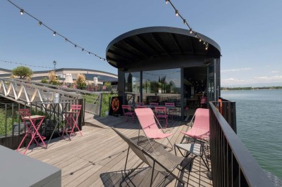 Miniature Location salle Tain-l'Hermitage (Drôme) - La Péniche #24 Terrasse en bois avec tables et chaises pliantes roses sous de grands parasols, entourée de plantes vertes.
