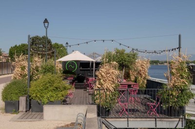 Miniature Location salle Tain-l'Hermitage (Drôme) - La Péniche #31 Terrasse en bois avec tables et chaises pliantes roses sous de grands parasols, entourée de plantes vertes.