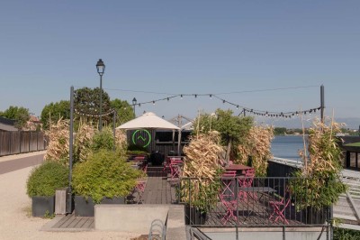 Miniature Location salle Tain-l'Hermitage (Drôme) - La Péniche #34 Terrasse en bois avec tables et chaises pliantes roses sous de grands parasols, entourée de plantes vertes.
