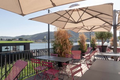Miniature Location salle Tain-l'Hermitage (Drôme) - La Péniche #37 Terrasse en bois avec tables et chaises pliantes roses sous de grands parasols, entourée de plantes vertes.