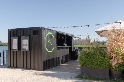 Miniature Location salle Tain-l'Hermitage (Drôme) - La Péniche #38 Terrasse en bois avec tables et chaises pliantes roses sous de grands parasols, entourée de plantes vertes.