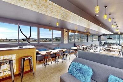 Miniature Location salle Tain-l'Hermitage (Drôme) - La Péniche #4 Terrasse ensoleillée avec tables et chaises pliantes roses sous de grands parasols, entourée de plantes vertes.