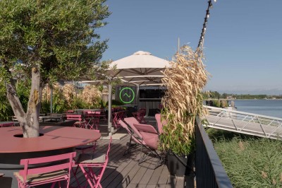 Miniature Location salle Tain-l'Hermitage (Drôme) - La Péniche #36 Terrasse ensoleillée avec tables et chaises pliantes roses sous de grands parasols, entourée de plantes vertes.