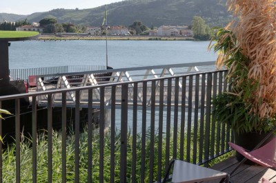 Miniature Location salle Tain-l'Hermitage (Drôme) - La Péniche #40 Terrasse ensoleillée avec tables et chaises pliantes roses sous de grands parasols, entourée de plantes vertes.