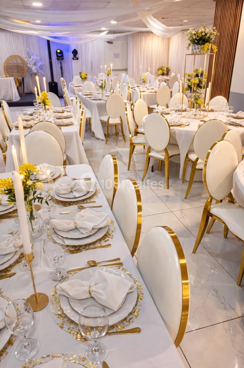 Salle de réception élégante avec tables dressées, chaises blanches et dorées, décorations florales jaunes et blanches.