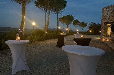 Chaises blanches alignées en extérieur face à une arche décorée, avec vue sur un paysage vallonné et des arbres.