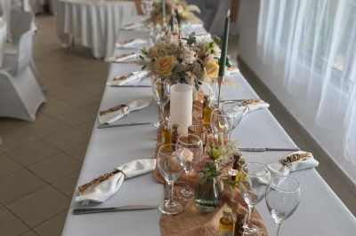 Chaises blanches alignées en extérieur face à une arche décorée, avec vue sur un paysage vallonné et des arbres.
