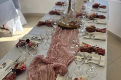 Chaises blanches alignées en extérieur face à une arche décorée, avec vue sur un paysage vallonné et des arbres.
