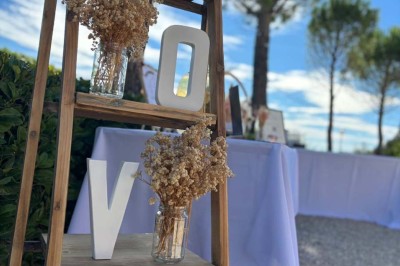 Chaises blanches alignées en extérieur face à une arche décorée, avec vue sur un paysage vallonné et des arbres.