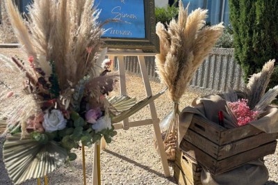 Chaises blanches alignées en extérieur face à une arche décorée, avec vue sur un paysage vallonné et des arbres.