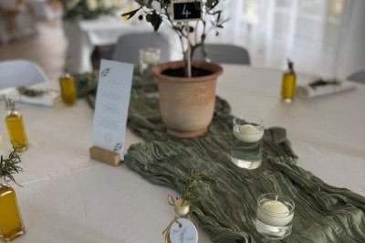 Chaises blanches alignées en extérieur face à une arche décorée, avec vue sur un paysage vallonné et des arbres.