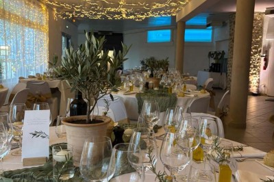 Chaises blanches alignées en extérieur face à une arche décorée, avec vue sur un paysage vallonné et des arbres.