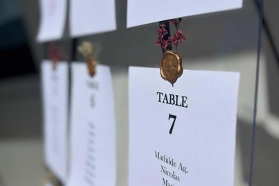 Chaises blanches alignées en extérieur face à une arche décorée, avec vue sur un paysage vallonné et des arbres.