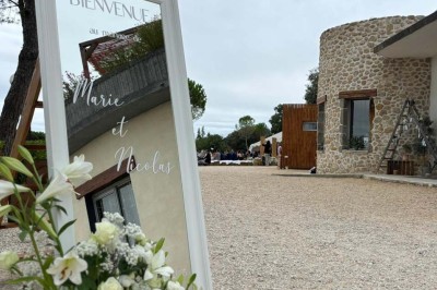 Chaises blanches alignées en extérieur face à une arche décorée, avec vue sur un paysage vallonné et des arbres.