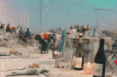 Chaises blanches alignées en extérieur face à une arche décorée, avec vue sur un paysage vallonné et des arbres.