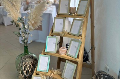 Chaises blanches alignées en extérieur face à une arche décorée, avec vue sur un paysage vallonné et des arbres.