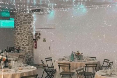 Chaises blanches alignées en extérieur face à une arche décorée, avec vue sur un paysage vallonné et des arbres.