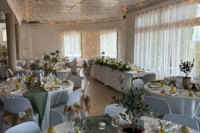 Chaises blanches alignées en extérieur face à une arche décorée, avec vue sur un paysage vallonné et des arbres.