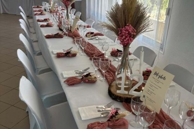 Chaises blanches alignées en extérieur face à une arche décorée, avec vue sur un paysage vallonné et des arbres.