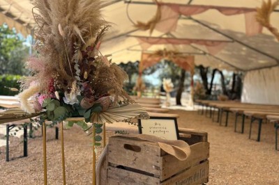 Chaises blanches alignées en extérieur face à une arche décorée, avec vue sur un paysage vallonné et des arbres.