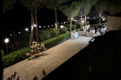 Chaises blanches alignées en extérieur face à une arche décorée, avec vue sur un paysage vallonné et des arbres.