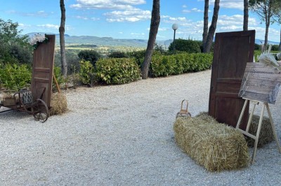 Chaises blanches alignées en extérieur face à une arche décorée, avec vue sur un paysage vallonné et des arbres.