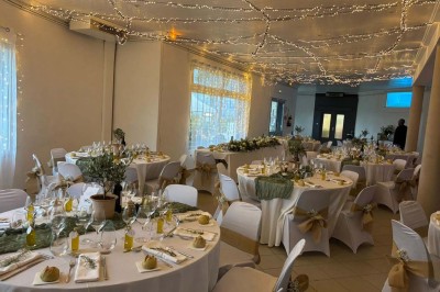 Chaises blanches alignées en extérieur face à une arche décorée, avec vue sur un paysage vallonné et des arbres.
