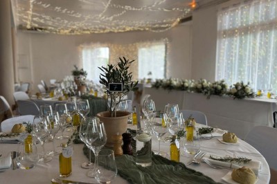 Chaises blanches alignées en extérieur face à une arche décorée, avec vue sur un paysage vallonné et des arbres.