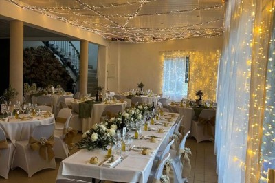 Chaises blanches alignées en extérieur face à une arche décorée, avec vue sur un paysage vallonné et des arbres.