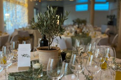 Chaises blanches alignées en extérieur face à une arche décorée, avec vue sur un paysage vallonné et des arbres.