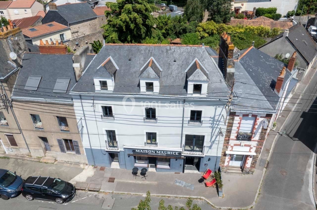 Vue aérienne d'une rue avec des bâtiments résidentiels, dont une maison avec une devanture commerciale et des voitures…