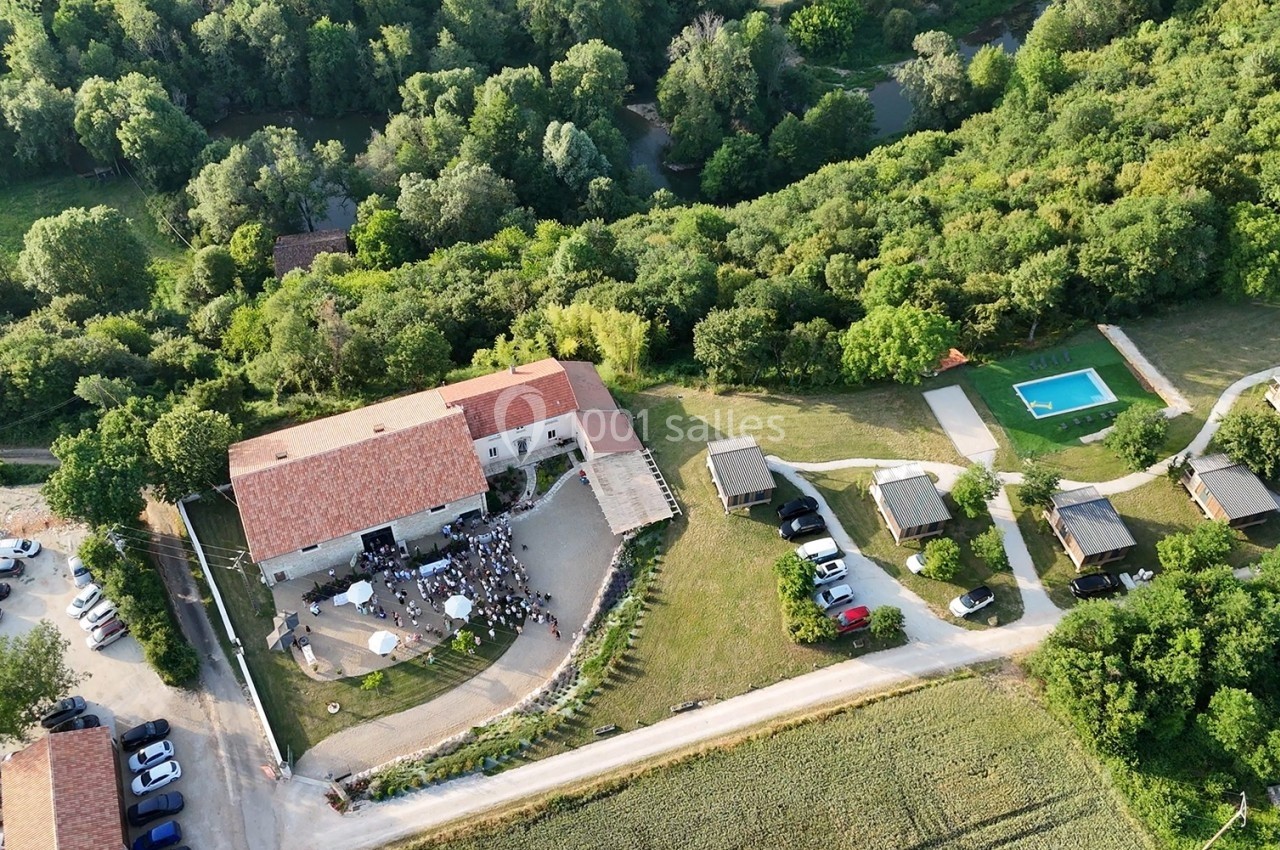 Vue aérienne d'un domaine rural avec bâtiments, piscine, parking et espaces verts entourés de forêt.