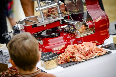 Miniature Location salle Bioussac (Charente) - Le Domaine de la Riche #69 Trancheuse rouge en action avec des tranches de jambon déposées sur une table, vue partielle d'un enfant au premier plan.