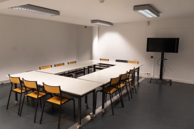 Miniature Location salle Bègles (Gironde) - La Salle Bolieu #3 Salle vide avec parquet en bois, murs blancs, écran de projection et plafond industriel avec éclairage suspendu.