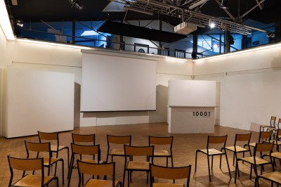 Miniature Location salle Bègles (Gironde) - La Salle Bolieu #7 Salle vide avec parquet en bois, murs blancs, écran de projection et plafond industriel avec éclairage suspendu.