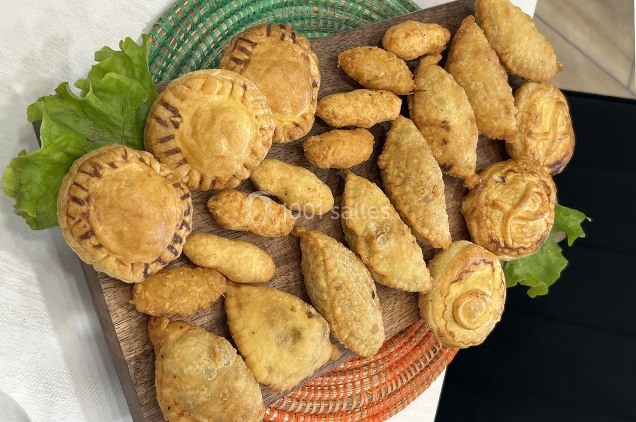 Assortiment de pâtisseries salées variées disposées sur un plateau en bois, décoré de feuilles de laitue.