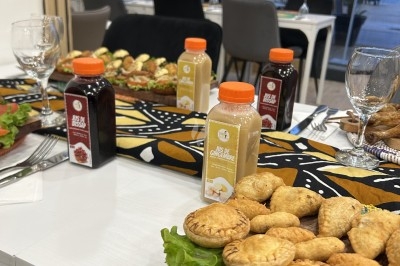Bouteilles de jus variés sur une table décorée, entourées de plats salés et de verres vides.