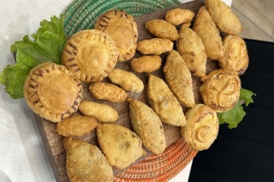 Assortiment de petits chaussons salés et feuilletés disposés sur un plateau en bois avec des feuilles de salade.