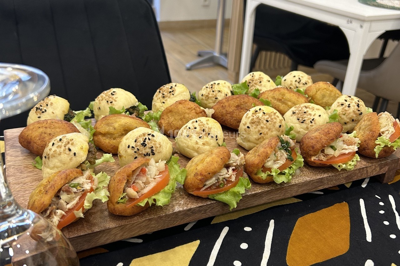 Plateau de mini sandwichs variés avec garnitures de légumes, salade et pain garni de graines de sésame.
