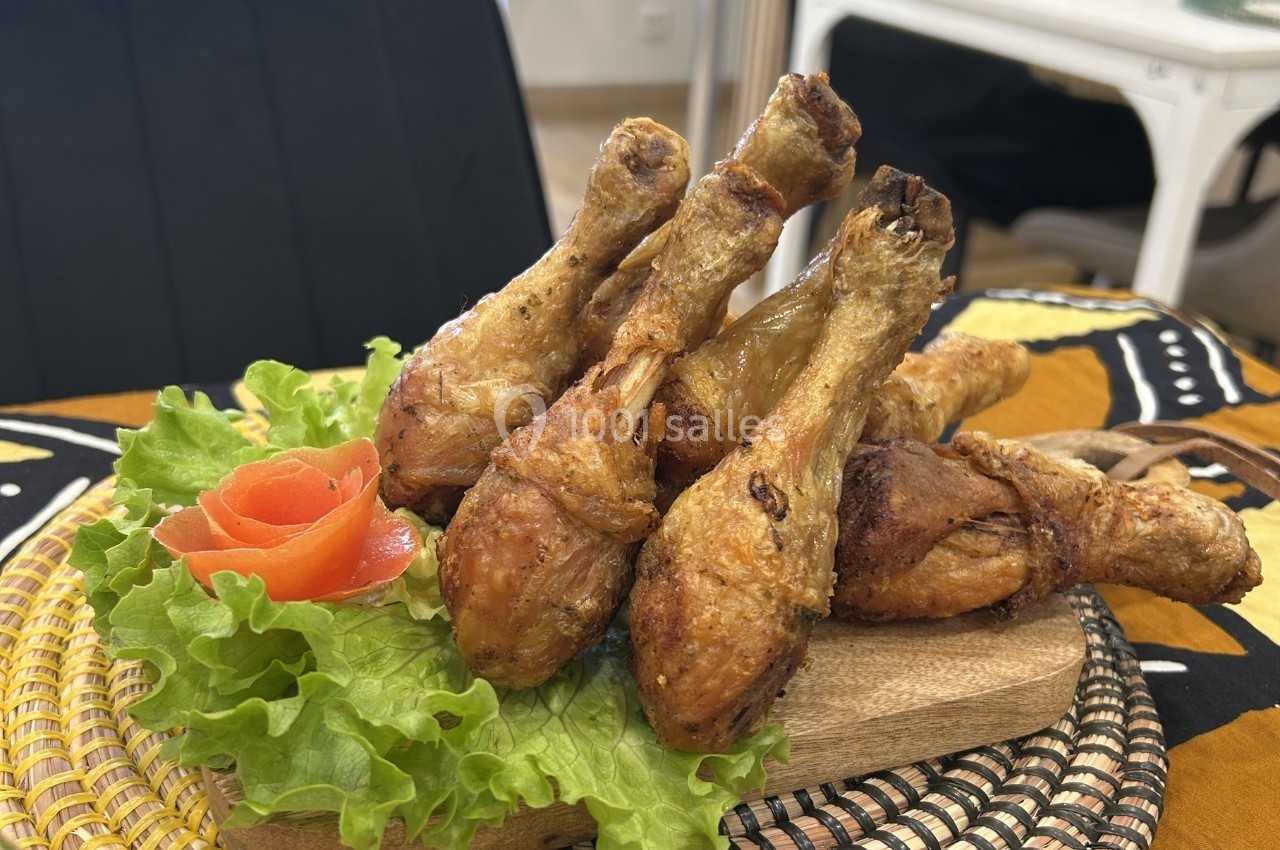 Pilons de poulet grillés disposés sur un lit de laitue avec une garniture de tomate en forme de rose.