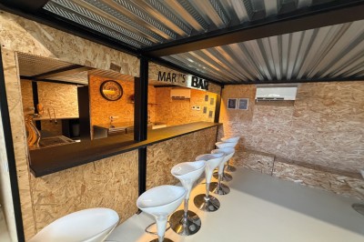 Table élégamment dressée avec verres, bougies et bouquet de fleurs séchées dans une ambiance tamisée.