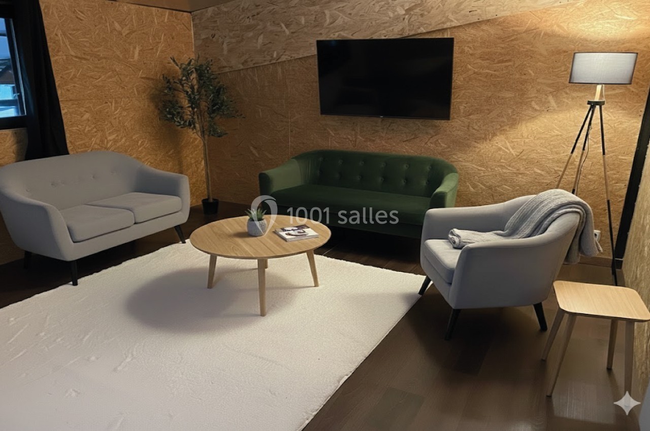 Salon moderne avec murs en bois, canapé vert, fauteuils gris, table basse ronde, tapis blanc et éclairage doux.