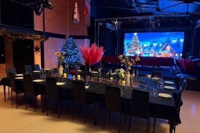 Salle de spectacle avec scène éclairée, artistes en représentation et public assis dans des fauteuils rouges.