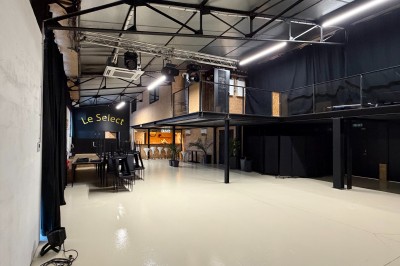 Salle de spectacle avec scène éclairée, artistes en représentation et public assis dans des fauteuils rouges.