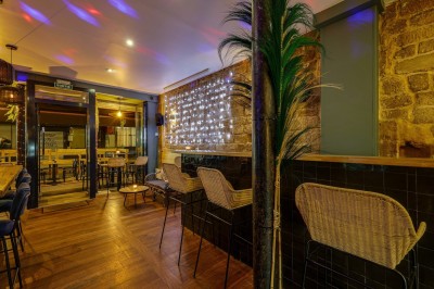 Bouteilles de vin variées alignées sur un comptoir en bois, avec un fond de bar décoré et éclairé.