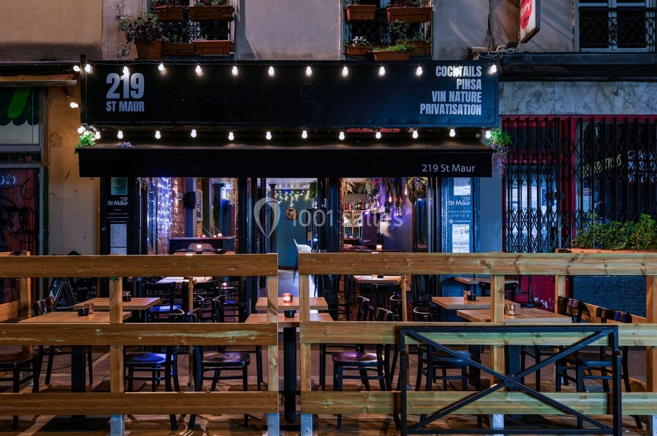Terrasse en bois et façade éclairée d'un bar-restaurant avec enseigne ’219 St Maur’ dans une rue urbaine.