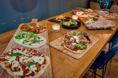 Bouteilles de vin variées alignées sur un comptoir en bois, avec un fond de bar décoré et éclairé.