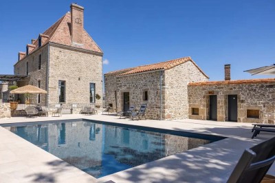 Un âne et un bélier se touchent le museau dans un pré verdoyant sous un ciel dégagé.